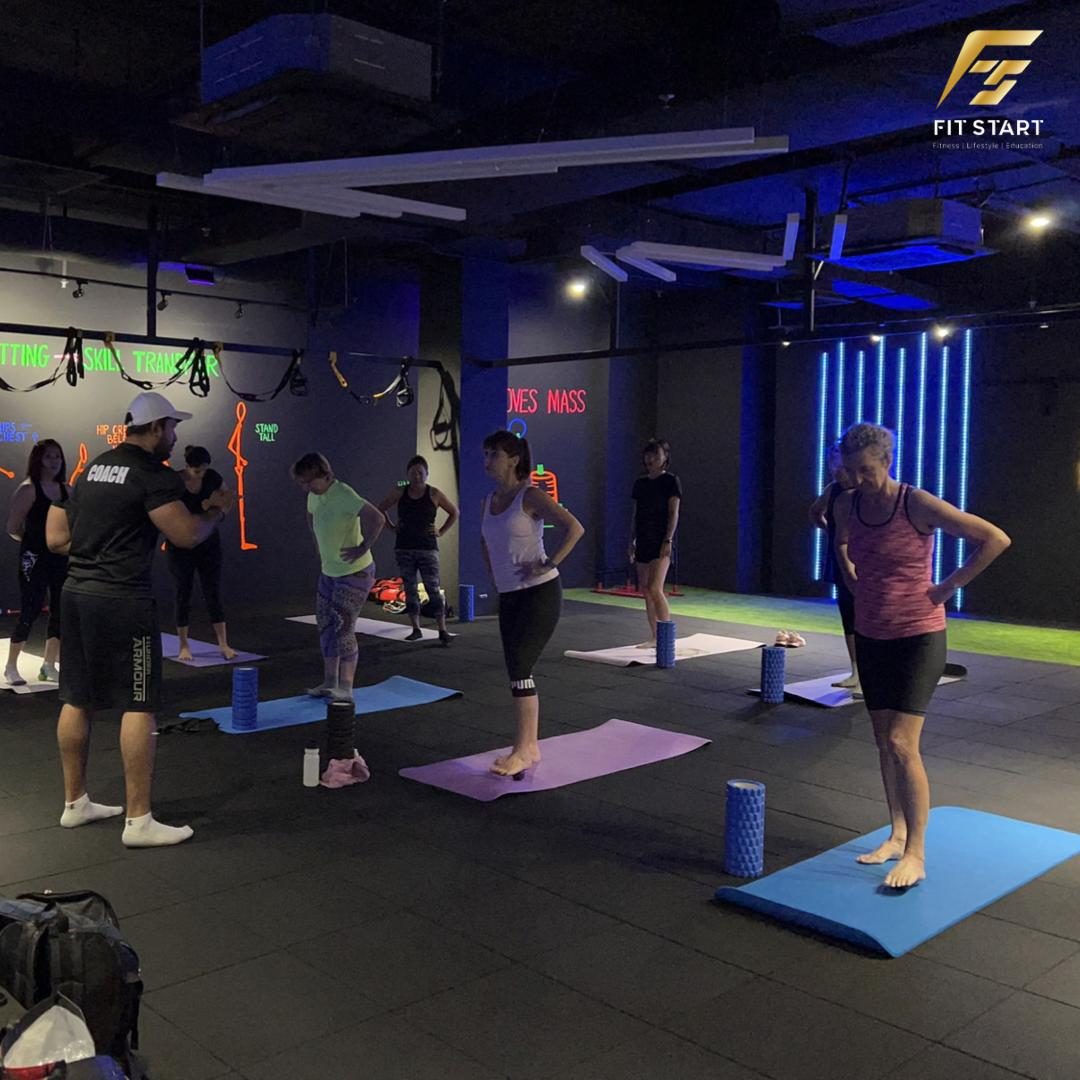 Coach guiding a mobility class with foam rollers and mats