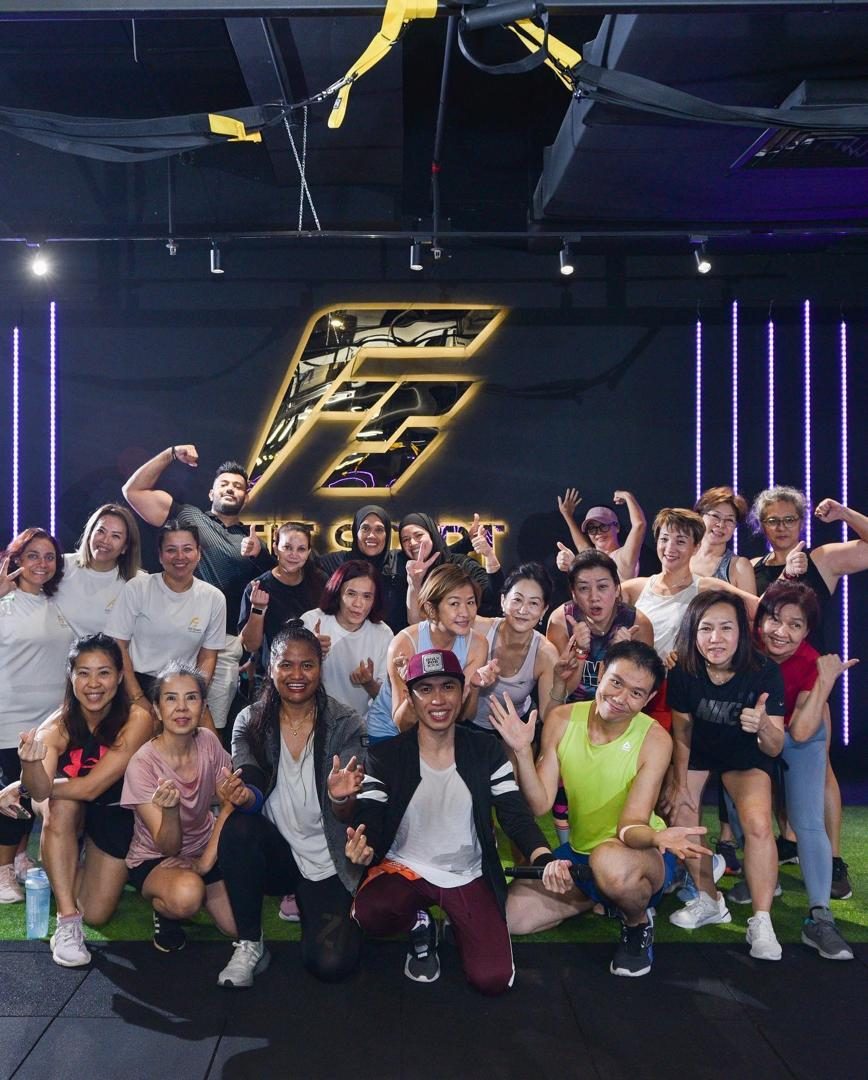 Group class posing together in the studio under the Fit Start logo