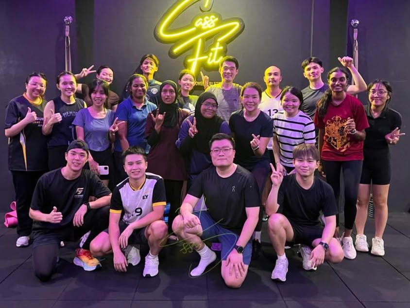 Group class posing in front of the Cass Fit neon sign